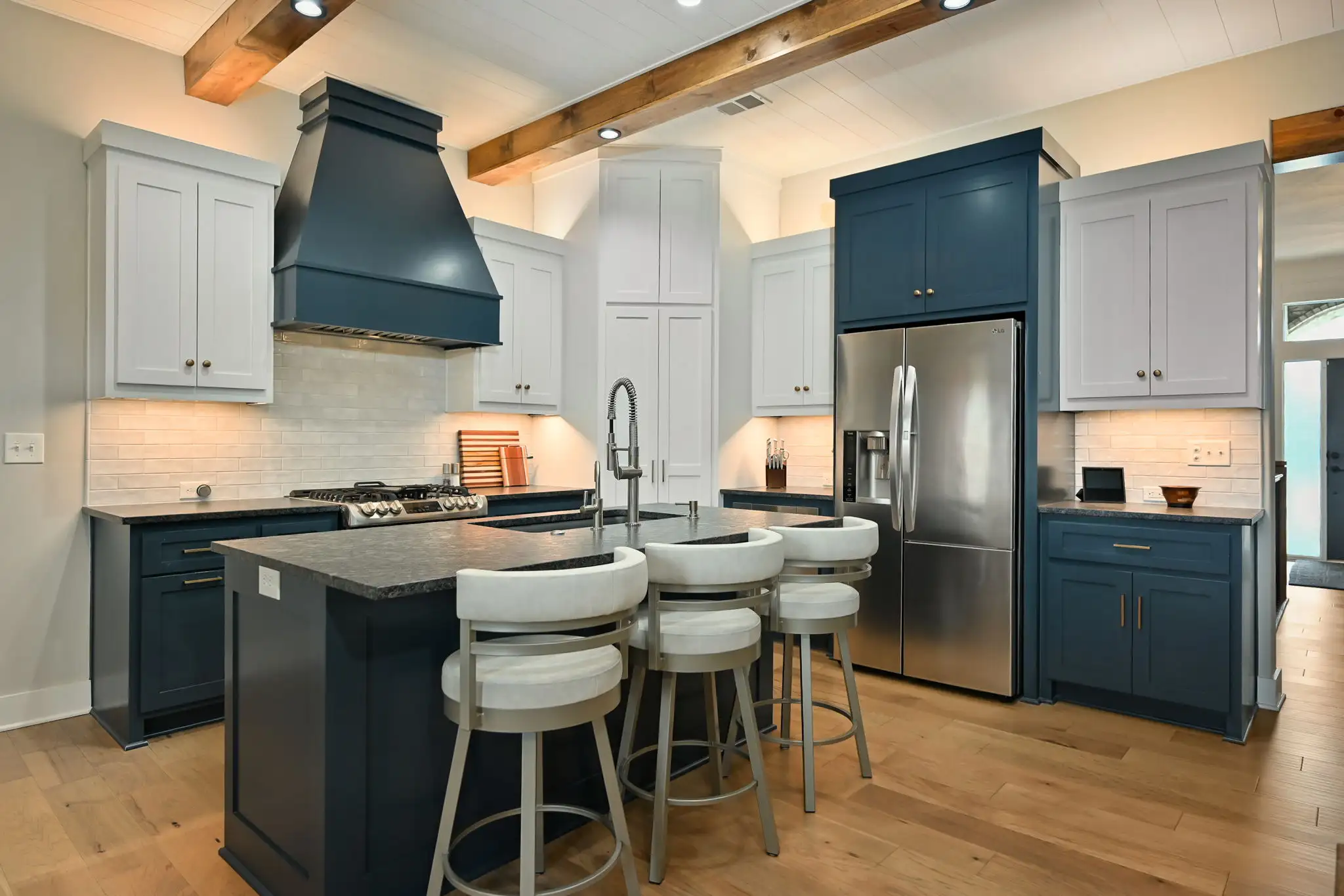 Kitchen with white and blue cabinetry, large island, and gas range in Cedar Creek home